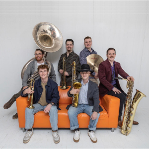 603 Brass Band seated on an orange couch with their instruments